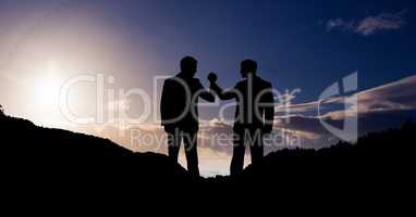 Businesspeople holding hands on mountains against sky