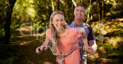 Happy couple riding cycle in forest