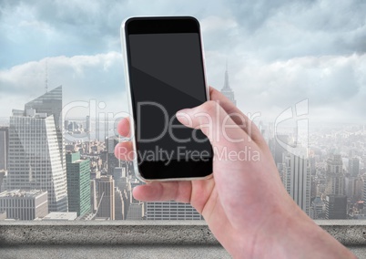 Hand with phone against blurry skyline