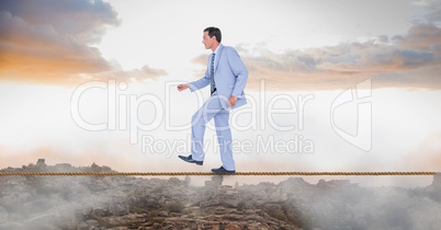 Businessman walking on rope over landscape