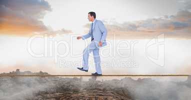 Businessman walking on rope over landscape