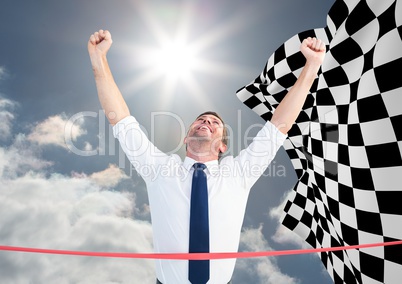 Business man at finish line against sky and checkered flag