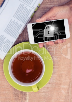Overhead of hand with phone and tea and white lock graphic and flare