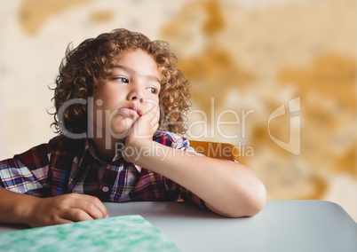 Bored boy at desk against blurry brown map