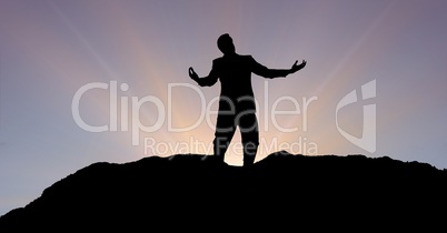 Silhouette businessman with arms outstretched on mountain during sunset