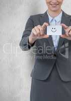 Midsection of businesswoman holding smiley face on card