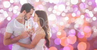 Passionate couple holding champagne flutes over bokeh