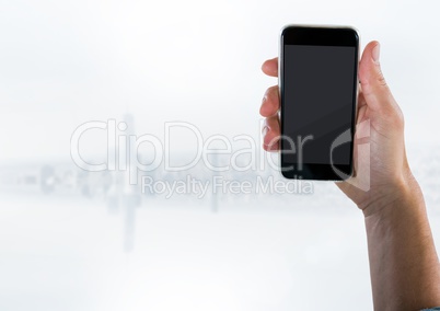 Hand with phone against blurry white skyline