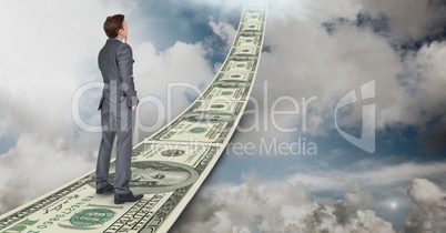 Digital composite image of businessman standing on money walkway in sky