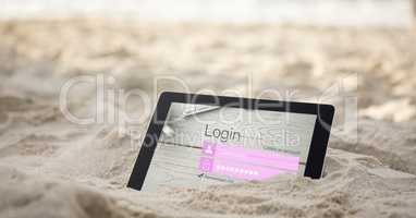 Digital tablet in sand with log in page on screen