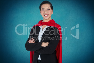 Portrait of businesswoman wearing cape while standing against blue background