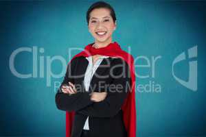 Portrait of businesswoman wearing cape while standing against blue background