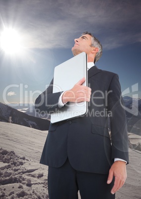 Business man with laptop looking up on mountain
