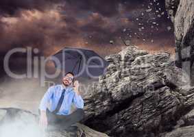 Business man legs crossed with umbrella and mist against falling rocks