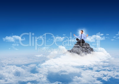Business man with flare meditating on mountain peak in the clouds with blue sky