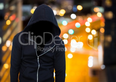 Anonymous man wearing hood in front of night city