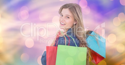 Smiling woman carrying shopping bags over bokeh