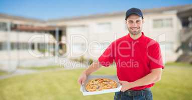 Portrait of smiling delivery man holding pizza boxes against buildings