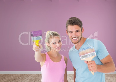 Couple with paintbrush and roller in room
