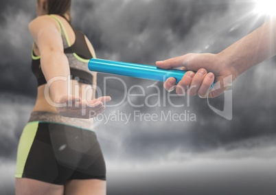 Relay runner and hand with blue baton and flare against stormy sky