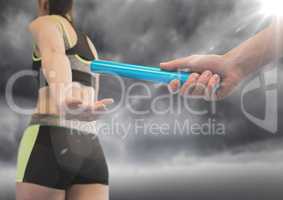 Relay runner and hand with blue baton and flare against stormy sky