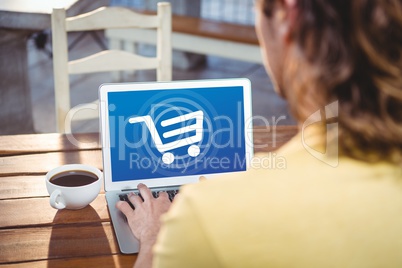 back view of man working with laptop with shopping cart on screen