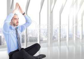 Business man with hands over head meditating with flare against blurry white window