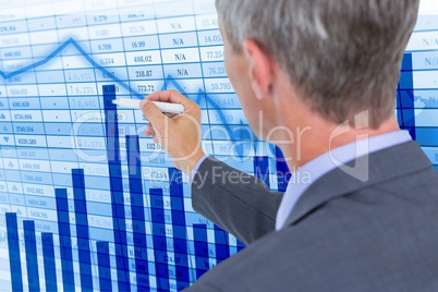 Digital composite image of businessman making graphs on screen