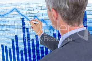 Digital composite image of businessman making graphs on screen