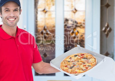 Happy deliveryman in the door of the house showing the pizza