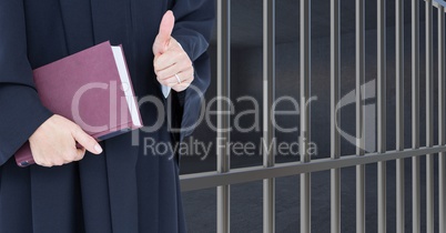 Judge holding book in front of prison bars cell