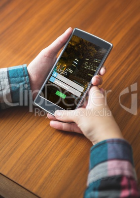 hands with phone on a table, login on the screen