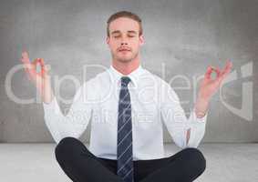 Business man meditating against grey wall