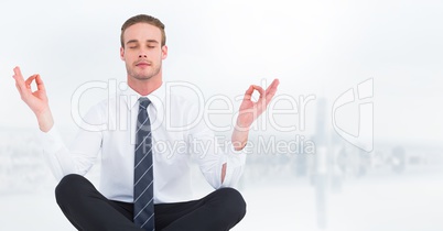 Business man meditating against blurry white skyline