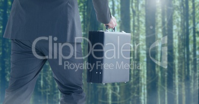 Businessman legs walking in forest with briefcase