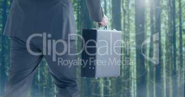 Businessman legs walking in forest with briefcase