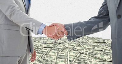 Business people shaking hands with money in background