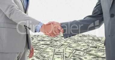 Business people shaking hands with money in background