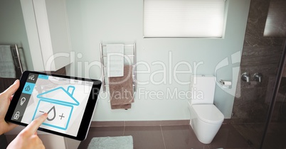 Hand using smart home application on digital tablet in washroom