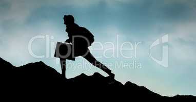 Silhouette business person walking on mountain against sky