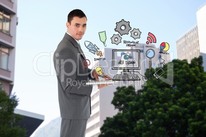 Confident businessman holding laptop by web design icons