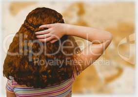 Back of girl with hand on hair against blurry brown map