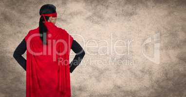 Back of business woman superhero with hands on hips against cream background with grunge overlay