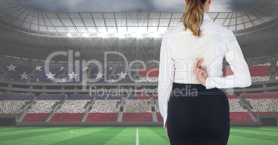 Rear view of businesswoman crossing fingers at stadium