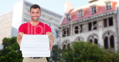 Portrait of smiling delivery man holding pizza boxes against buildings