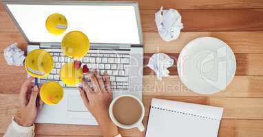 Digital composite image of hands using laptop while emojis flying over table