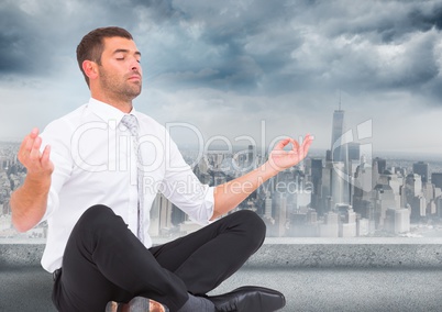 Business man with meditating against grey skyline and clouds