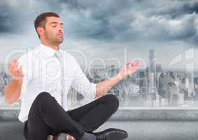 Business man with meditating against grey skyline and clouds
