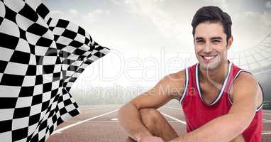 Male runner sitting on track against flares with checkered flag