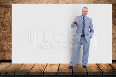 Portrait of senior businessman gesturing while standing against blank billboard in office